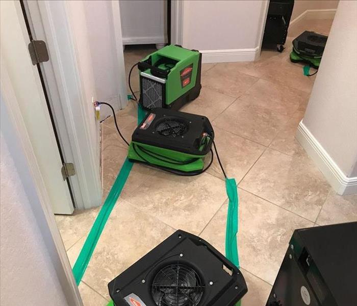 Green air movers in a hallway with white walls. 