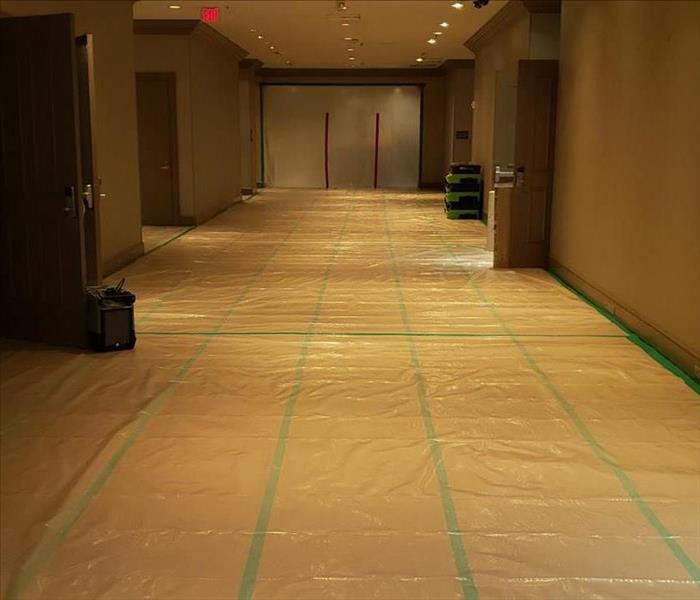 Plastic cover on carpet in large commercial hallway.