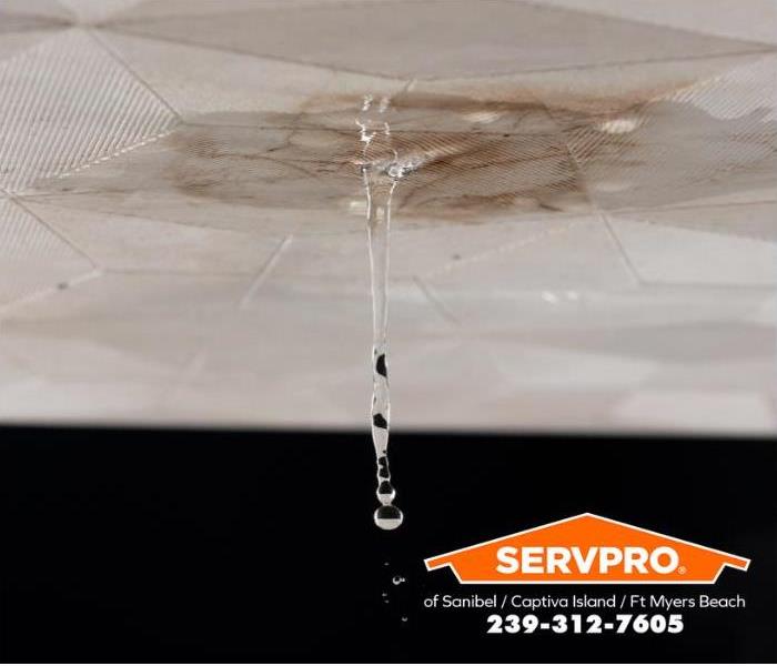 Water from a broken pipe drips through the tile board on a ceiling into the room below.